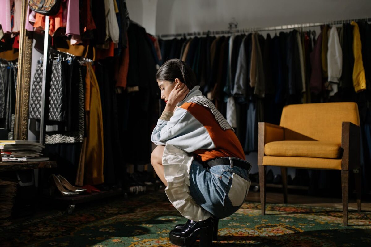 A stylish woman posing thoughtfully in a vintage clothing store, showcasing retro fashion.