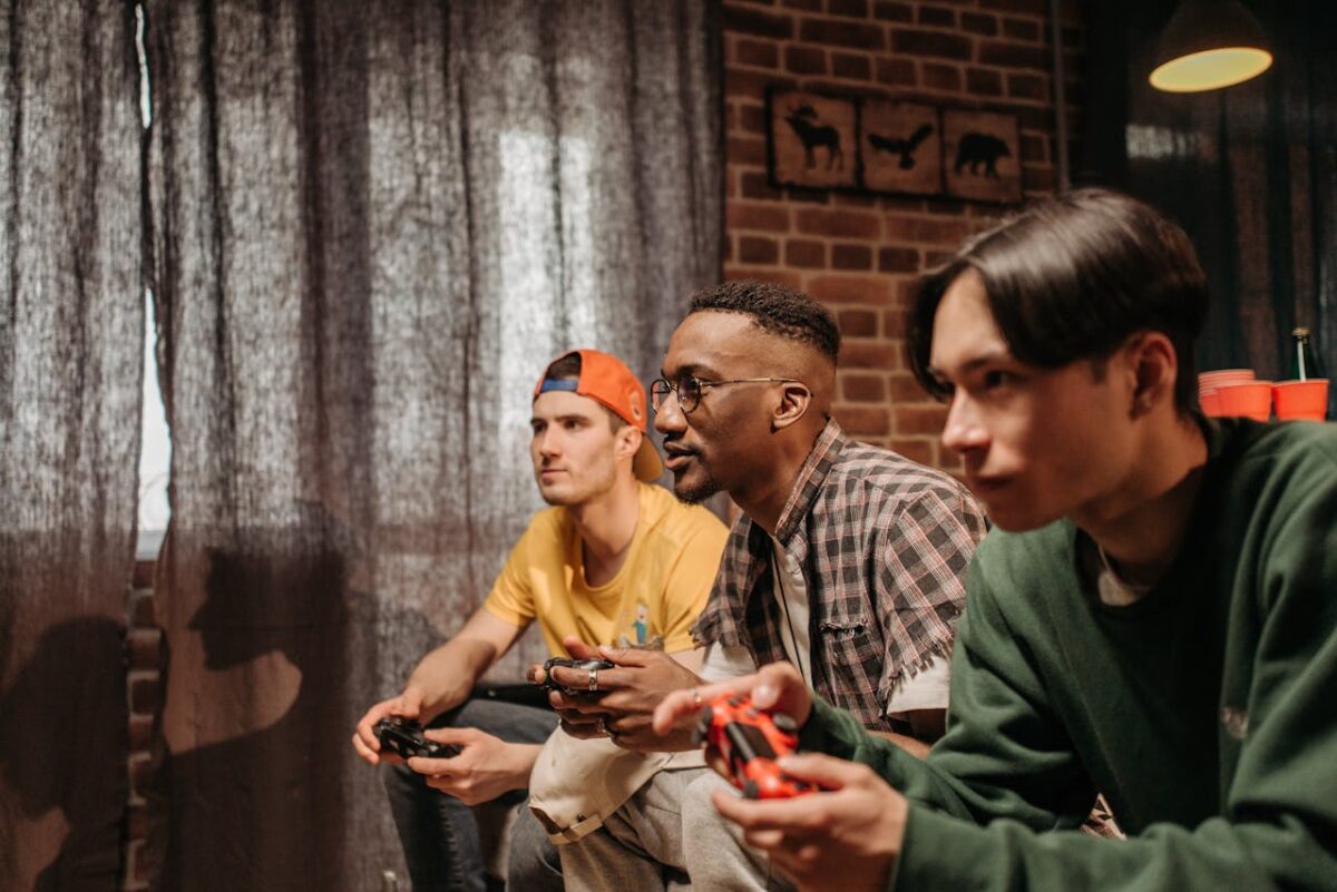 Three men focused on playing video games with controllers indoors.