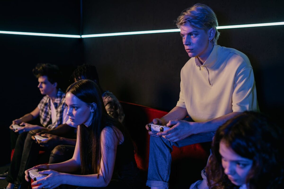 Group of focused teenagers playing video games indoors, immersed in teamwork and concentration.