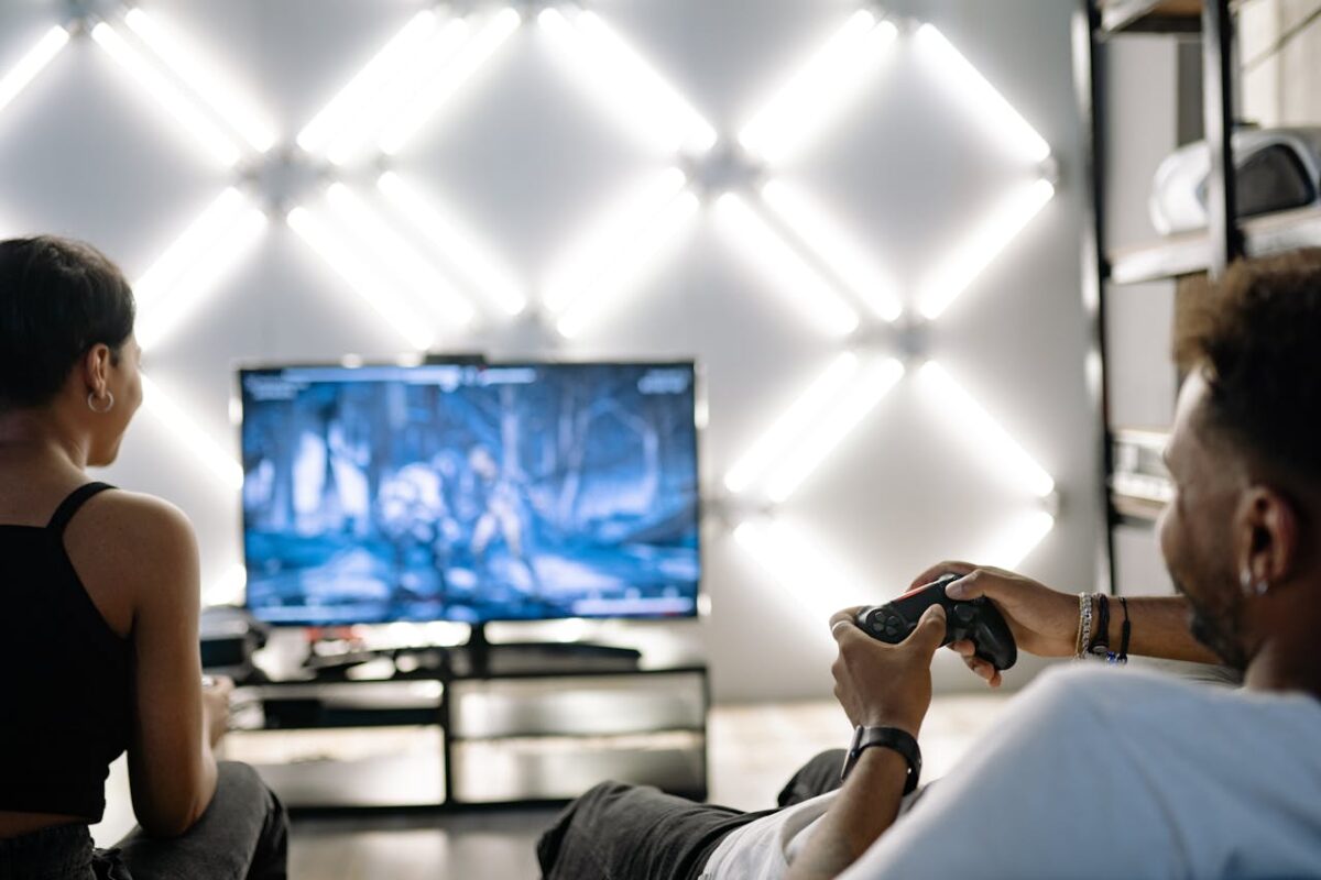 Two adults are having fun playing video games in a stylish, modern living room with LED lighting.